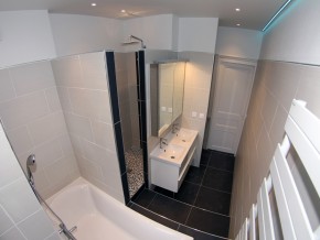 Salle de douche avec baignoire, lavabo double, miroir avec placard et sèche serviettes